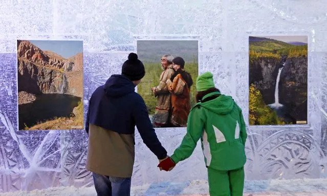 A couple looks at photographs from Siberian photographers on a wall of ice, during an exhibition that is part of the “Magic Ice of Siberia” International Competition of Snow Sculpture along the banks of the Yenisei River in Krasnoyarsk January 13, 2015. The ice sculpting competition, which is in its third edition, will see teams from Russian and China competing against each other from January 13 to 19. (Photo by Ilya Naymushin/Reuters)
