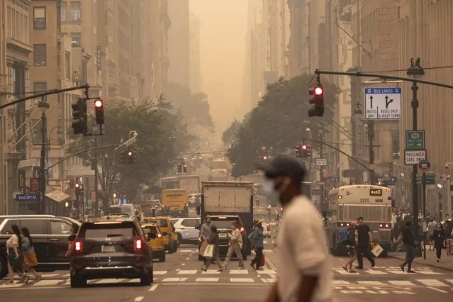 A man wears a mask as he crosses an intersection in a haze-filled sky of Manhattan, New York, Wednesday, June. 7, 2023. Smoke from Canadian wildfires poured into the U.S. East Coast and Midwest on Wednesday, covering cities in both nations in an unhealthy haze, holding up flights at major airports and prompting people to fish out pandemic-era face masks. (Photo by Yuki Iwamura/AP Photo)
