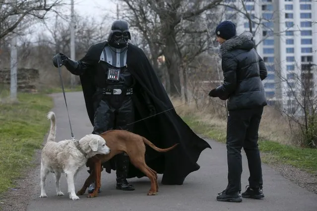 Darth Mykolaiovych Vader, who is dressed as the Star Wars character Darth Vader, poses for a picture as he speaks to a woman while walking his dog in a park in Odessa, Ukraine, December 3, 2015. (Photo by Valentyn Ogirenko/Reuters)