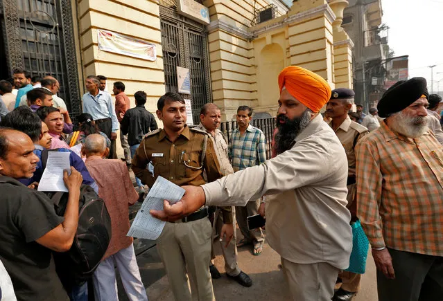 A man argues with a police officer as people queue outside a branch of the State Bank of india  to exchange old high denomination bank notes in Old Delhi, India, November 10, 2016. (Photo by Cathal McNaughton/Reuters)