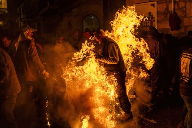A man waves a burning broom next to people during “Los Escobazos” Festival on December 07, 2024 in Jarandilla de la Vera, Spain. Although the origin of “Los Escobazos” is unknown it is believed that goat shepherds used to walk down at night from Gredos mountains to the village lighting their way with broom torches to celebrate the Virgin's Immaculate Conception Day (December 8th). Is a festival of national tourist interest celebrated every year on December 7th extending into the early hours of December 8th: people make bonfires in the streets and start a battle with burning “Escobones” (brooms) followed by the procession of the “Estandarte” (Banner) of the Immaculate Conception. (Photo by Pablo Blazquez Dominguez/Getty Images)
