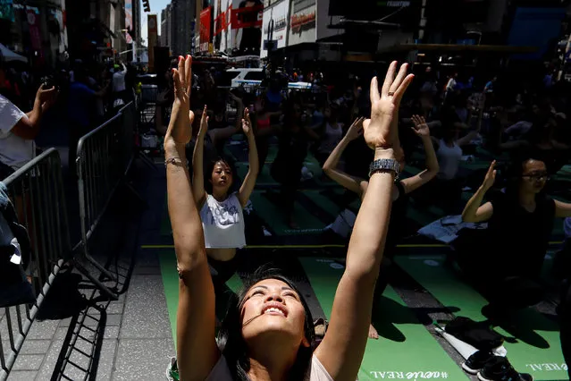 People participate in a yoga class during an annual Solstice event in the Times Square in New York City, U.S., June 21, 2018. (Photo by Brendan McDermid/Reuters)