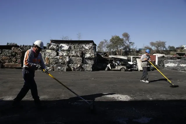 In this Wednesday, November 11, 2015 photo, Orlando Rodriguez, right, and Jose Garate sweep at Aadlen Brothers Auto Wrecking, also known as U Pick Parts, in the Sun Valley section of Los Angeles. (Photo by Jae C. Hong/AP Photo)