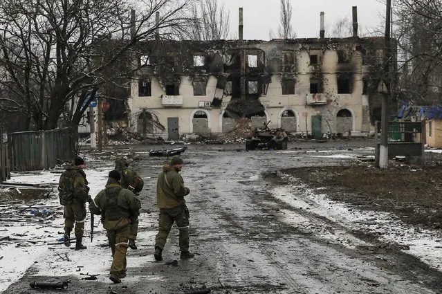 Members of the armed forces of the separatist self-proclaimed Donetsk People's Republic walk near a building destroyed during battles with the Ukrainian armed forces in Vuhlehirsk, Donetsk region, February 4, 2015. (Photo by Maxim Shemetov/Reuters)