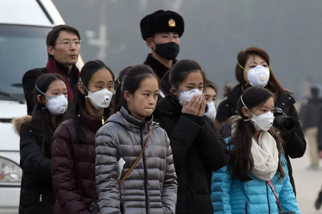 Young tourists wear masks as they stand near a Chinese Paramilitary policeman in Tiananmen Square in Beijing, China, Saturday, December 19, 2015. Smog built up in the Chinese capital as the second red alert of the month went into effect, forcing many cars off the roads and restricting factory production. (Photo by Ng Han Guan/AP Photo)