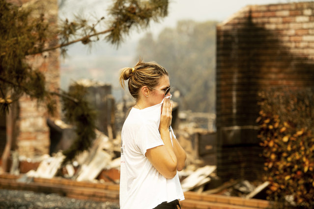 A woman, who declined to give her name, surveys damage to her grandmother's house after the Carr Fire burned through Redding, Calif., on Friday, July 27, 2018. Officials say the extremely erratic wildfire in and around the city of Redding is growing rapidly amid scorching temperatures, low humidity and windy conditions. (Photo by Noah Berger/AP Photo)