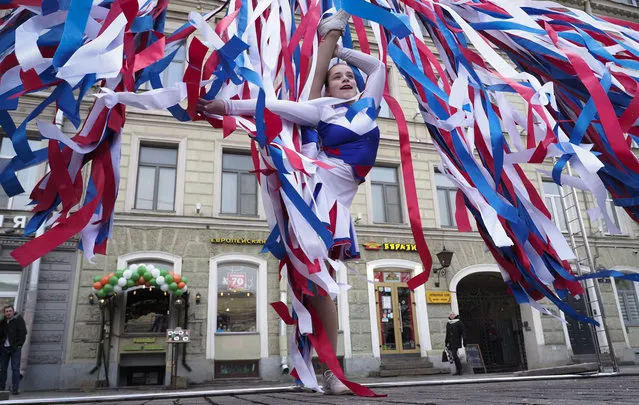 A dancer performs among the ribbons of the colours of the Russian flag during celebration of the anniversary of Crimea annexation from Ukraine in 2014, in St. Petersburg, Russia, Thursday, March 18, 2021. Residents of cities in Crimea and Russia are holding gatherings to commemorate the seventh anniversary of Russia's annexation of the Black Sea peninsula from Ukraine. (Photo by Dmitri Lovetsky/AP Photo)