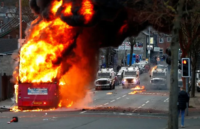 Police vehicles are seen behind a hijacked bus burns on the Shankill Road as protests continue in Belfast, Northern Ireland, April 7, 2021. (Photo by Jason Cairnduff/Reuters)