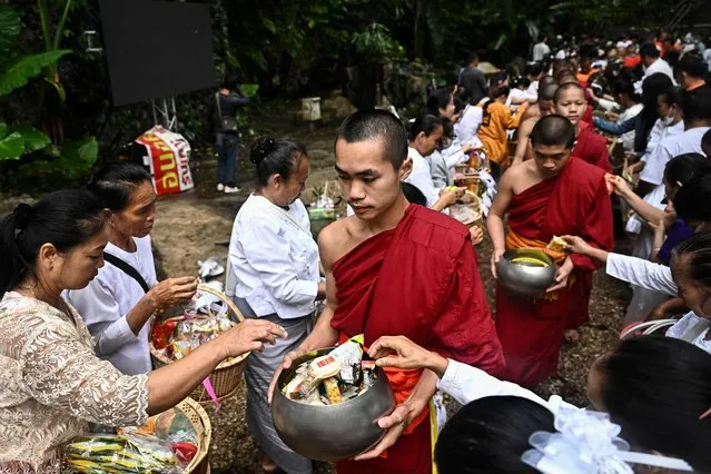 Relatives and friends of members of the Thai “Wild Boars” youth football team take part in a Buddhist alms ceremony outside the Tham Luang Cave in Mae Sai district in the northern province of Chiang Rai on July 10, 2023, to mark the fifth anniversary of the boys' rescue from the flooded cave. Five years after twelve young footballers trapped in a Thai cave were dramatically pulled to safety in a rescue watched around the world, local officials re-opened more of the site on July 10. (Photo by Lillian Suwanrumpha/AFP Photo)