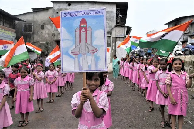 Children wave Indian flags at their school premises in Mumbai, India as they cheer for the successful landing of India’s moon craft Chandrayaan-3, on the moon surface, Tuesday, August 22, 2023. India’s previous attempt to land a robotic spacecraft near the moon’s little-explored south pole ended in failure in 2019. (Photo by Rajanish Kakade/AP Photo)