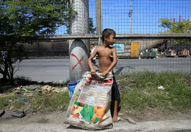 A boy holds a sack while clutching a banana under his armpit while scavenging trash in metro Manila, Philippines September 6, 2016. (Photo by Romeo Ranoco/Reuters)