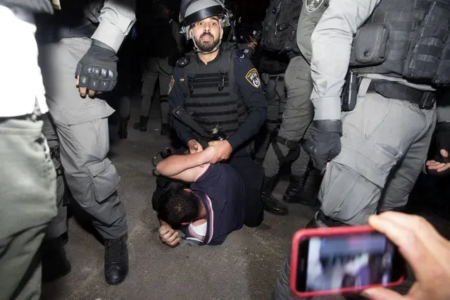 An Israeli police officer restrains a Palestinian during a protest on the eve of a court verdict that may forcibly evict Palestinian families from their homes in the Sheikh Jarrah neighborhood of Jerusalem, Wednesday, May 5, 2021. Several Palestinian families in Sheikh Jarrah have been embroiled in a long-running legal battle with Israeli settler groups trying to acquire property in the neighborhood near Jerusalem's famed Old City. (Photo by Maya Alleruzzo/AP Photo)