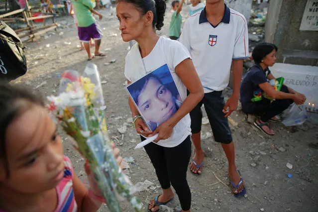 The mother of Angelo Lafuente, whose body, riddled with bullets, was found by a filthy river that feeds into the Manila bay, holds his picture as she visits his grave on the All Saints Day in Manila, Philippines November1, 2016. (Photo by Damir Sagolj/Reuters)