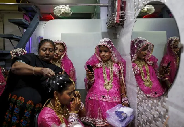 A Muslim bride gets her make-up done as another takes her picture at a beauty parlour before the start of a mass marriage ceremony in Mumbai, India, January 27, 2016. (Photo by Danish Siddiqui/Reuters)