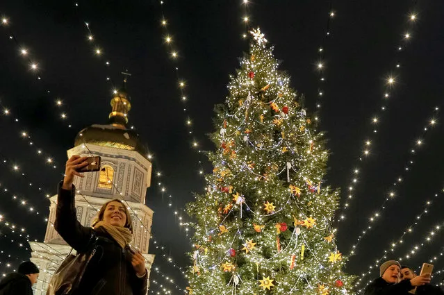 People take pictures next to an illuminated Christmas tree in front of the St. Sophia Cathedral in central Kiev, Ukraine, December 21, 2016. (Photo by Valentyn Ogirenko/Reuters)