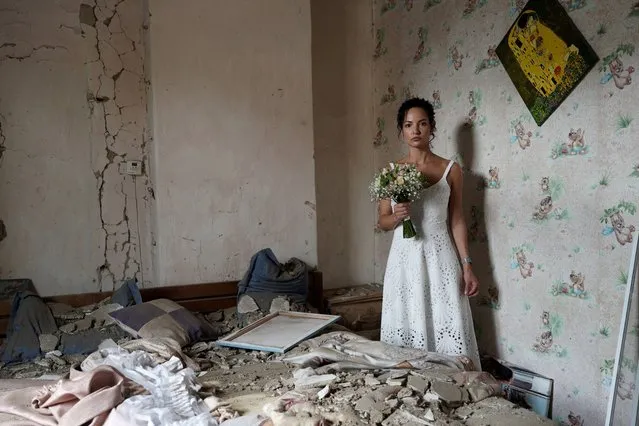 Daria Steniukova, 31, yoga coach poses for a picture during the wedding photo shooting in her bombed flat in Vinnytsya on July 16, 2022. Since the Russian invasion of Ukraine on February 24, 2022, Ukraine is experiencing an unprecedented rush to the altar: 9,120 marriages have been registered in 5 months in Kyiv, compared to the 1,110 registered during the same period in 2021. (Photo by Oleksandr Demianiv/AFP Photo)