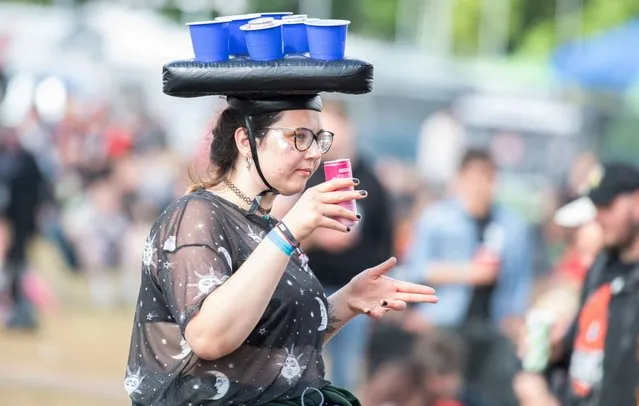 A festival goer carries some drinks on her head on day 2 of the Download PILOT festival at Donington Park on June 19, 2021 in Donington, England. Download Pilot is a 10,000 capacity festival part of a UK government test event to examine how Covid-19 transmission takes place in crowds. (Photo by Katja Ogrin/Getty Images)