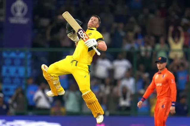 Australia's David Warner leaps to celebrate scoring a century during the ICC Men's Cricket World Cup match between Australia and Netherlands in New Delhi, India, Wednesday, October 25, 2023. (Photo by Manish Swarup/AP Photo)