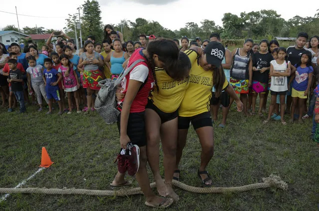 In this November 25, 2018 photo, an injured Guna woman is aid by her teammates after the tug-of-war competition of the second edition of the Panamanian indigenous games in Piriati, Panama. Events such as archery, swimming, wrestling and running are also a part of the games. (Photo by Arnulfo Franco/AP Photo)