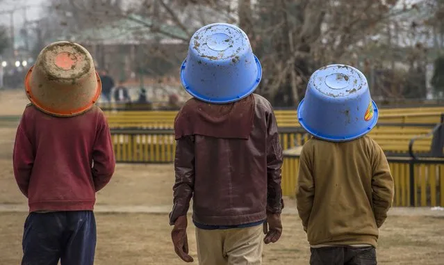 Kashmiri labourers cover their heads with buckets after dumping soil at the river bank during a cold day on December 10, 2018 in Srinagar, the summer capital of Indian administered Kashmir, India. Dry, cold weather continued in Kashmir valley with most places in the state recording sub-zero temperatures. (Photo by Yawar Nazir/Getty Images)