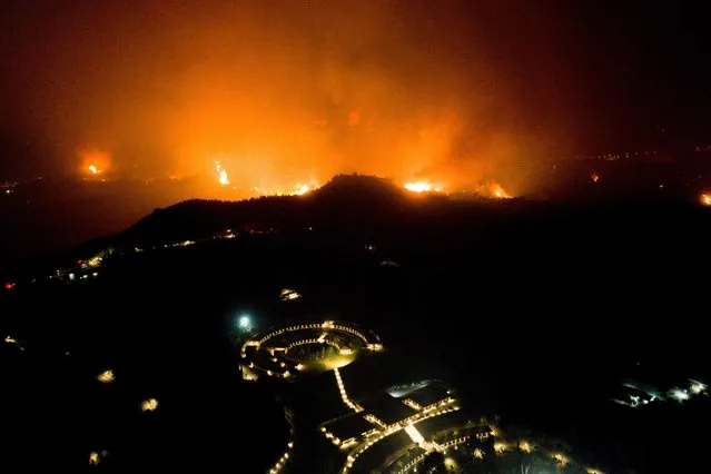 A wildfire approaches the Olympic Academy in ancient Olympia in western Greece on August 4, 2021. Greek firefighters have been battling several heatwave-fuelled forest infernos, including around Athens that have destroyed or damaged dozens of homes and businesses and forced the evacuation of villages, and others in the south and on the island of Euboea. (Photo by Eurokinissi/AFP Photo)