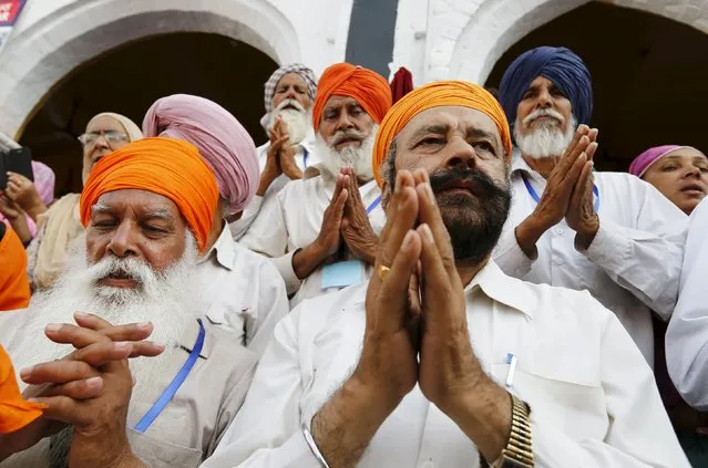 Sikh devotees gesture in prayer as the procession passes by during the Baisakhi festival at Panja Sahib shrine in Hassan Abdel April 13, 2015. (Photo by Caren Firouz/Reuters)