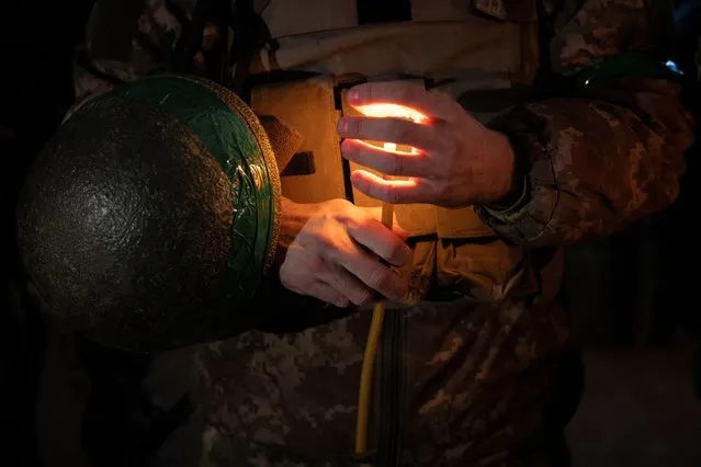 A Ukrainian soldier of the 14th Separate Mechanized Brigade holds a candle during a Christmas Eve service near the front line outside Kupiansk, Ukraine on December 24, 2023. (Photo by Thomas Peter/Reuters)