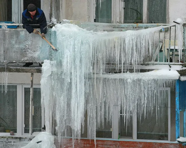 A worker knocks down icicles hanging from a residential house in Ivanovo, Russia on February 11, 2019. (Photo by Vladimir Smirnov/TASS)