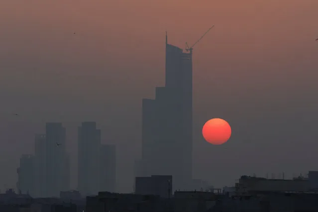 The first sun of the New Year rises behind the Bahria Icon Tower, in Karachi, Pakistan on January 1, 2024. (Photo by Akhtar Soomro/Reuters)