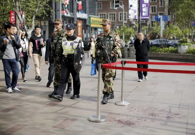A police officer and armed soldiers patrol the area where two people were injured after a knife-wielding attack near People's Square in central Shanghai April 17, 2015. The attacker was arrested by the police and the reason for the attack remains unknown, local media reported. (Photo by Carlos Barria/Reuters)
