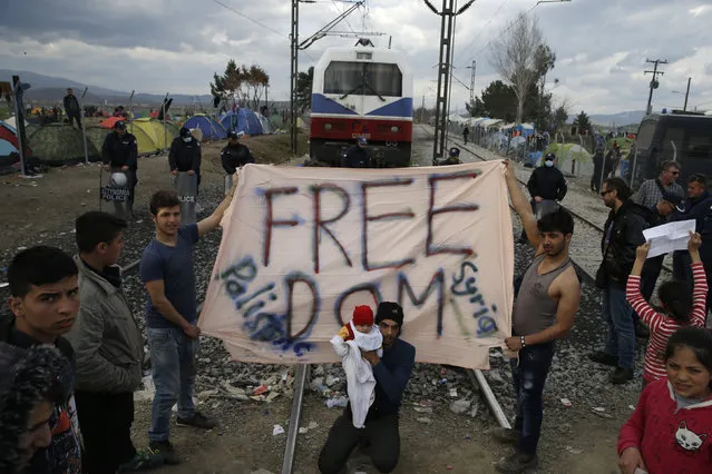 Migrants hold a banner as they block the railway track at the Greek-Macedonian border, near the village of Idomeni, Greece March 3, 2016. (Photo by Marko Djurica/Reuters)