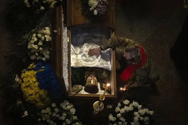 A Ukrainian army chaplain pays his respects at the coffin of Ukrainian serviceman and famous Ukrainian poet Maksym Kryvtsov, who was killed in a battle with the Russian troops, during the funeral ceremony in St. Michael Cathedral in Kyiv, Ukraine, Thursday, January 11, 2024. (Photo by Efrem Lukatsky/AP Photo)