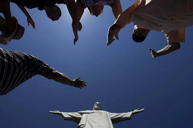 Visitors raise their arms to pray below the Christ Redeemer statue on January 21, 2014. (Photo by Felipe Dana/Associated Press)