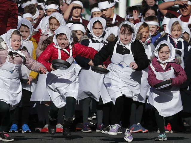 Children start for their annual Shrove Tuesday trans-Atlantic pancake race in the town of Olney, in Buckinghamshire, England, Tuesday, March 5, 2019. Every year women clad in aprons and head scarves from Olney and the city of Liberal, in Kansas, USA, run their respective legs of the race with pancakes in their pans. According to legend, the Olney race started in 1445 when a harried housewife arrived at church on Shrove Tuesday still clutching her frying pan with a pancake in it. (Photo by Frank Augstein/AP Photo)
