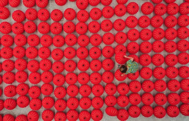This aerial photo taken on September 24, 2021 shows a worker producing red lanterns ahahead of China's National Day in Danzhai, southwestern Guizhou province. (Photo by AFP Photo/China Stringer Network)