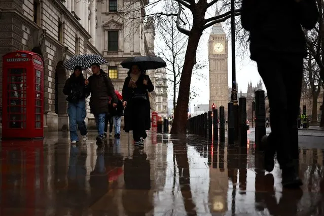 Pedestrians hold umbrellas as they walk in the rain past the Elizabeth Tower, commonly known as Big Ben, in central London on December 19, 2023. (Photo by Henry Nicholls/AFP Photo)