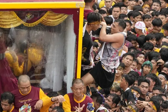 A devotee kisses the crucifix of the Black Nazarene during its annual procession which was resumed after a three-year suspension due to the coronavirus pandemic on Tuesday, January 9, 2024 in Manila, Philippines. (Photo by Aaron Favila/AP Photo)