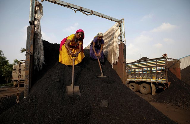 Workers unload coal from a supply truck at a yard on the outskirts of Ahmedabad, India October 12, 2021. (Photo by Amit Dave/Reuters)