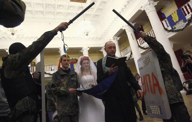Ukrainian anti-government protesters Bogdan (2nd L), 21, and Yulia, 25, get married during their wedding ceremony in a city municipality building occupied by anti-government protesters in Kiev February 5, 2014. (Photo by David Mdzinarishvili/Reuters)