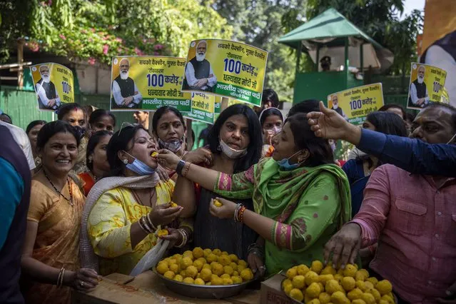 Members of India's ruling Bharatiya Janata Party (BJP) distribute sweets to celebrate 1 billion doses of COVID-19 vaccine in New Delhi, India, Thursday, October 21, 2021. India has administered 1 billion doses of COVID-19 vaccine, passing a milestone for the South Asian country where the delta variant fueled its first crushing surge this year. (Photo by Altaf Qadri/AP Photo)