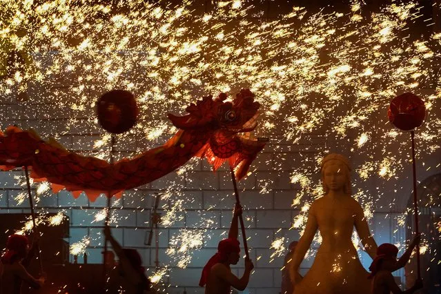 Fire dragon dancers perform under a shower of sparks from molten iron during a temple fair at the Shijingshan Amusement Park in Beijing, Monday, February 12, 2024. Chinese people are enjoying a weeklong holiday for the Lunar New Year and visiting various temple fairs and carnivals held in the cities around China. (Photo by Andy Wong/AP Photo)