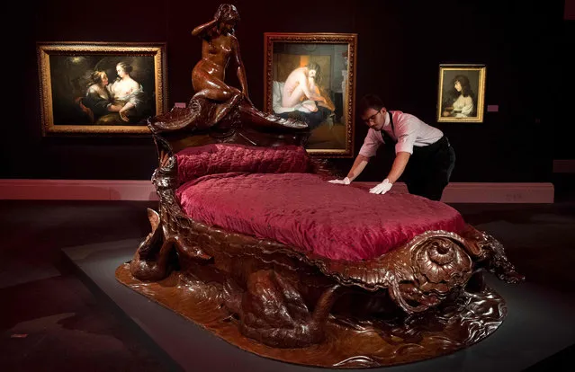 An employee of Sotheby' s auction house poses with a French carved mahogany bed from the second half of the 19 th century with an estimated price of 500,000-800,000 GBP (600,000-950,000 EUR; 600,000-1,000,000 USD) during a photocall in London on February 10, 2017 to promote Sotheby' s forthcoming Erotic: Passion & Desire sale in London on February 16. (Photo by Justin Tallis/AFP Photo)