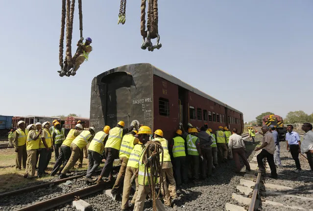 Rescue workers push a passenger coach on a track during a mock rescue drill at Sabarmati railway yard in Ahmedabad, India, March 17, 2016. (Photo by Amit Dave/Reuters)
