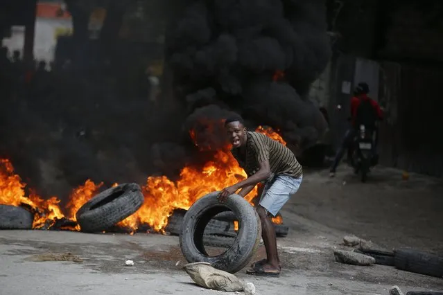 A protester adds tires to a burning barricade during a demonstration demanding the resignation of Prime Minister Ariel Henry, in Port-au-Prince, Haiti, Wednesday, February 7, 2024. (Photo by Odelyn Joseph/AP Photo)