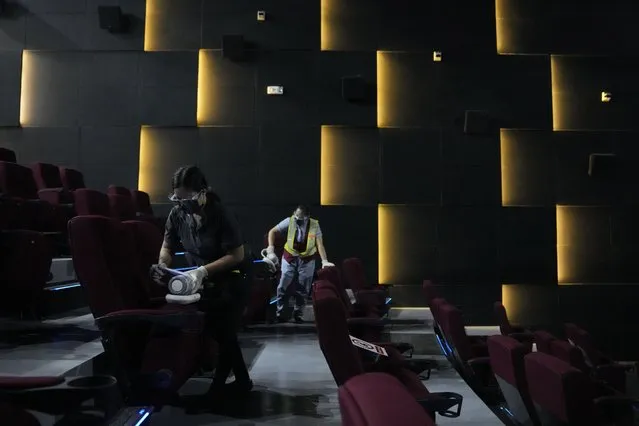 Employees sanitize a movie theatre as they prepare to reopen at the Eastwood mall in Quezon city, Philippines as government eases restrictions after a decline in Coronavirus cases in the country on Thursday, October 14, 2021. Several businesses were allowed to reopen in the next days as the country tries to revive the economy which have suffered due to the lockdowns to prevent the spread of COVID-19. (Photo by Aaron Favila/AP Photo)