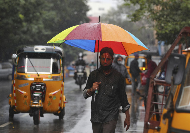 A man walks holding an umbrella in the rain in Hyderabad, India, Saturday, November 20, 2021. More than a dozen people have died and dozens are reported missing in the southern Indian state of Andhra Pradesh after days of heavy rains, authorities said. (Photo by Mahesh Kumar A./AP Photo)