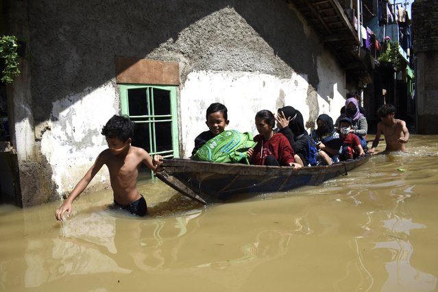 A family evacuate from their flooded home following heavy rain in Bandung on November 3, 2021. (Photo by Timur Matahari/AFP Photo)