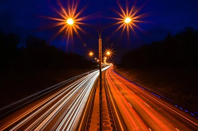 Automobiles move along the highway leaving light trails outside Moscow on November 15, 2021. (Photo by Yuri Kadobnov/AFP Photo)