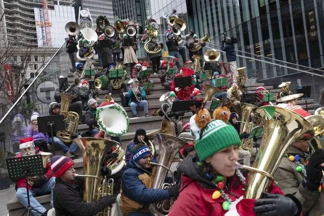Dozens of tuba musicians play Christmas music, Sunday, November 28, 2021, at Downtown Crossing in Boston. Boston's TubaChristmas has been happening for more than 40 years. It is one of more than 180 such celebrations throughout North America this year. (Photo by Michael Dwyer/AP Photo)