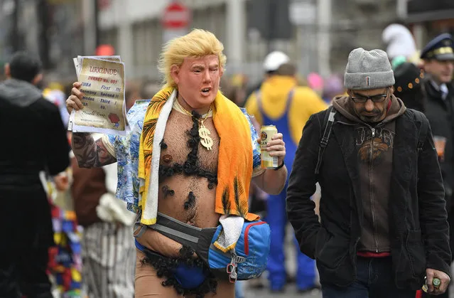 A man with a Donald Trump mask holds a paper reading ' Cuba first, Germany second, Sweden third, USA 69.' when tens of thousands revelers dressed in carnival costumes celebrate the start of the street-carnival in Cologne, Germany, Thursday, February 23, 2017. (Photo by Martin Meissner/AP Photo)